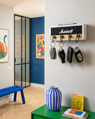 Wall-mounted white guitar amp key holder using real guitar plugs as keychains.