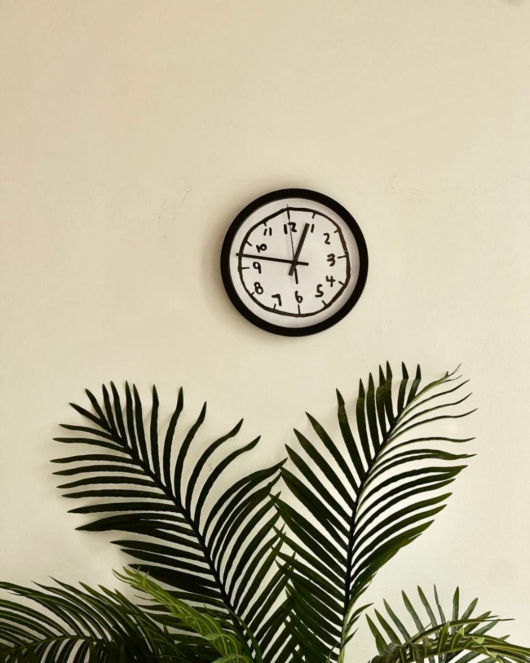 Aesthetic black and white doodle clock mounted on a neutral beige wall, perfect for living room or office decor.